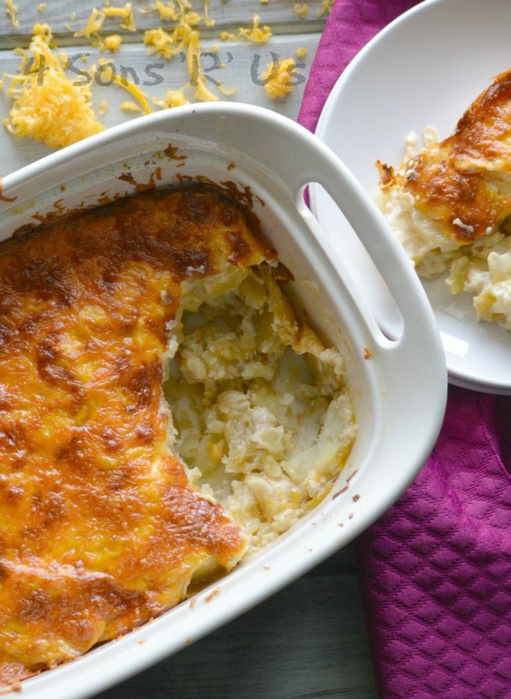 a casserole dish with cheese and potatoes in it on a purple towel next to two white plates