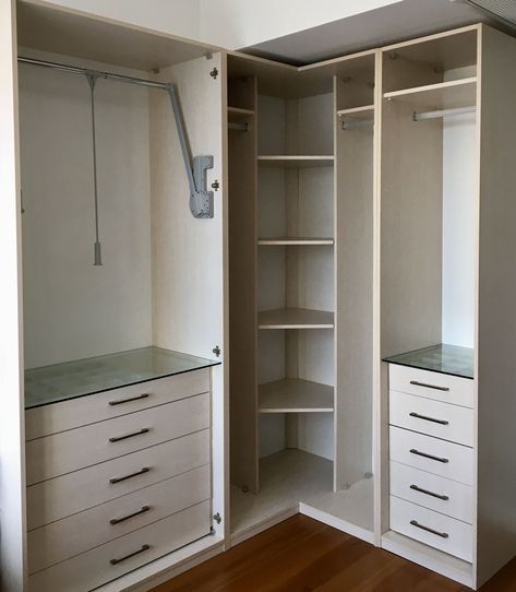 an empty walk in closet with white cabinets and drawers