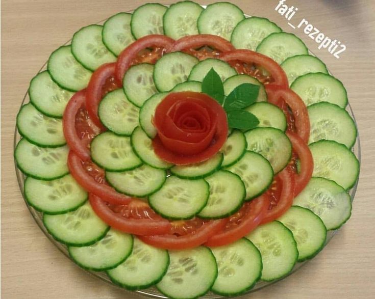 a plate with cucumbers and tomatoes arranged in the shape of a spiral on it