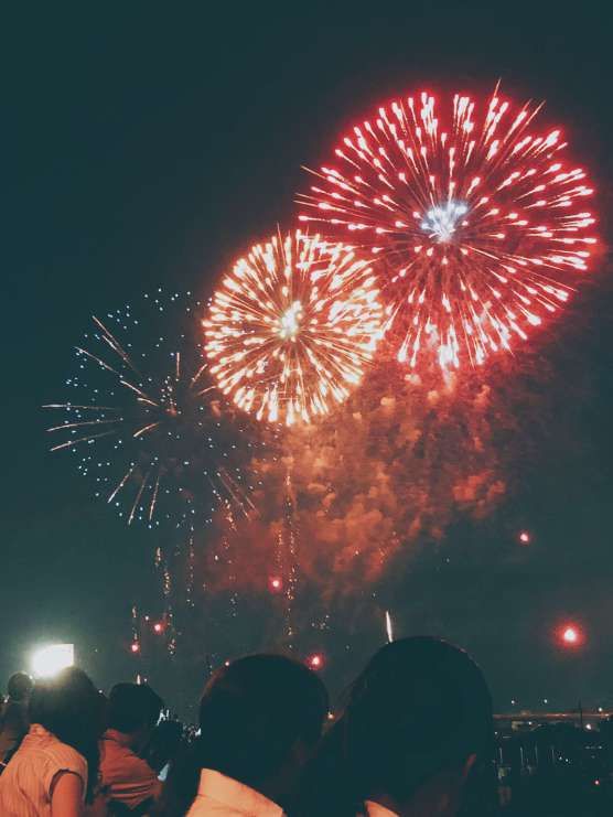 fireworks are lit up in the night sky with people looking at them and taking pictures