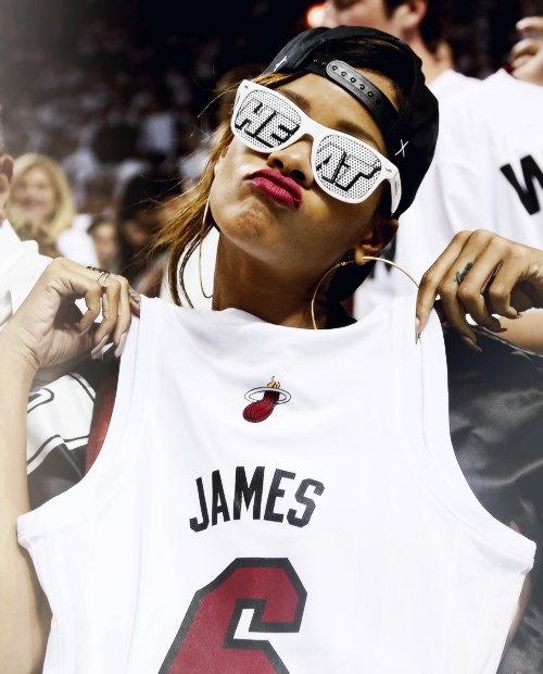 a woman with sunglasses on her face holding up a jersey