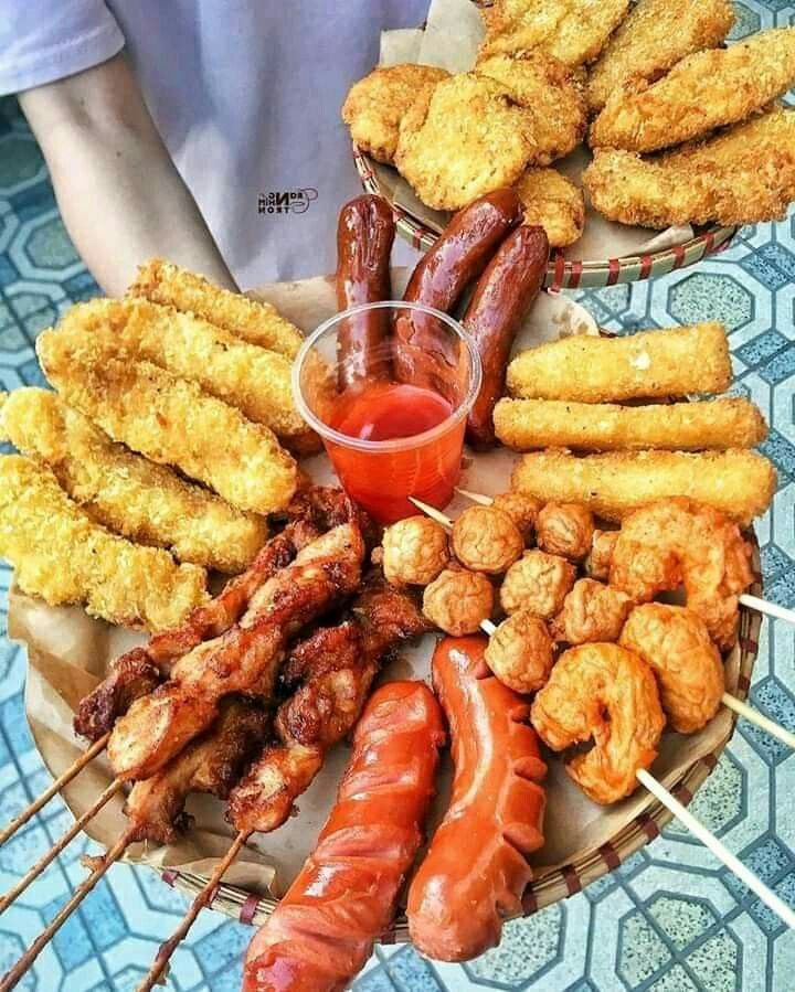 an assortment of meats on skewers with dipping sauce