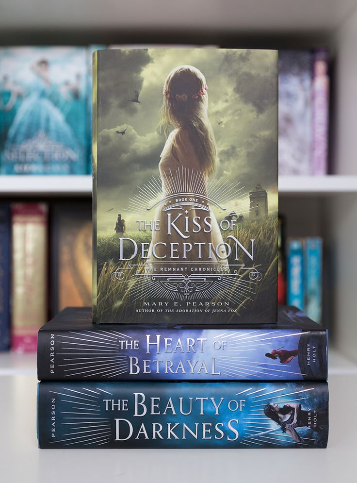 three books stacked on top of each other in front of a book shelf filled with books