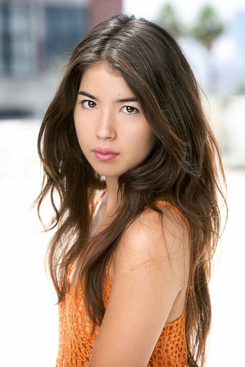 a woman in an orange top posing for a photo