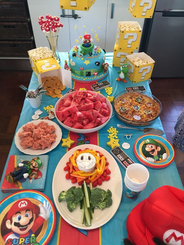 mario birthday party food and decorations on a table with plates, cups, napkins and candy