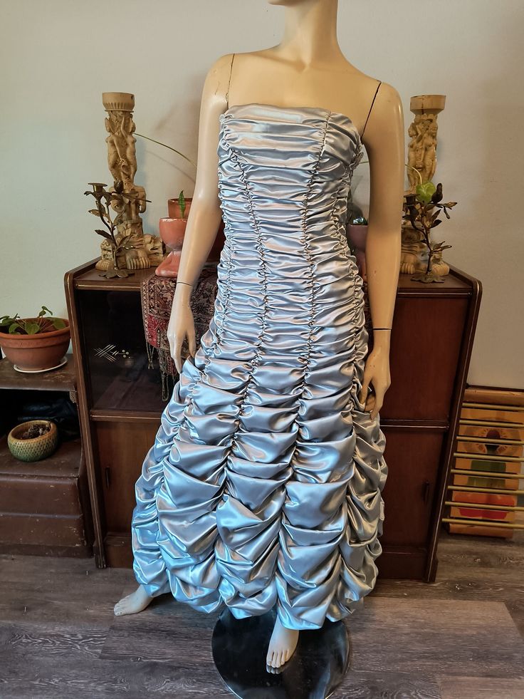 "Silver ruched dress by Jessica McClintock. This asymmetrical strapless dress is shorter in the front and longer in the back. Boning in front and back gives it a great fit. Side zipper closure. A beautiful, rare dress designed by an icon. Size 2 and best suited to a XS. Length 50\" in front 56\" back Bust 30\" Waist 26\" Dress is in great vintage condition. The bottom at the back is dirty, but would probably be alleviated with a dry cleaning. Price is reflective of condition. If you would like an international shipping quote or have any questions, please send me a message. I am constantly hitting the shops and sales to bring the finest in timeless vintage to the modern woman. I naturally gravitate towards funky patterns, bold colors, tailored silhouettes, and fabulous fabrics. My backgroun Red Formal Prom Dresses, 1960s Cocktail Dress, Purple Midi Skirt, Funky Patterns, Rare Dress, Jessica Mcclintock Dress, Steampunk Dress, Formal Prom Dress, Corpus Christi Tx