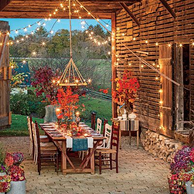 an outdoor dining area with lights strung from the roof and tables set for dinner outside