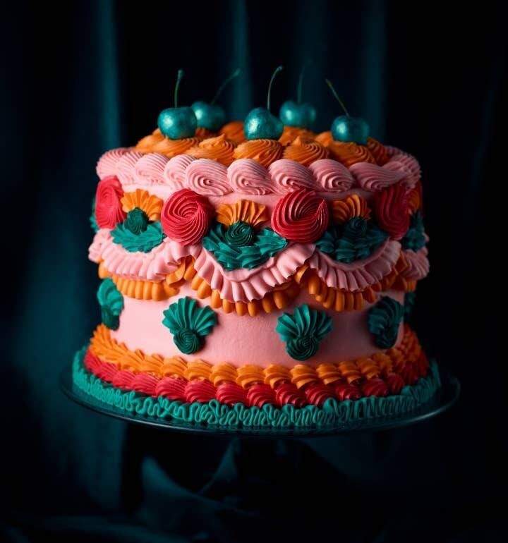 a multi - colored cake decorated with flowers and cherries