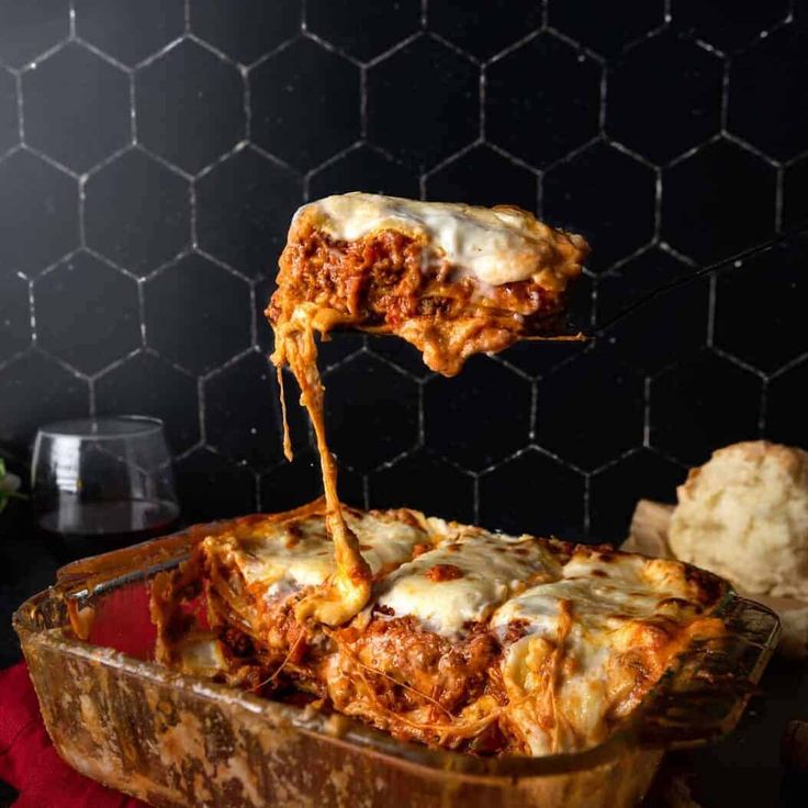 a spatula full of lasagna sauce being lifted from a casserole dish