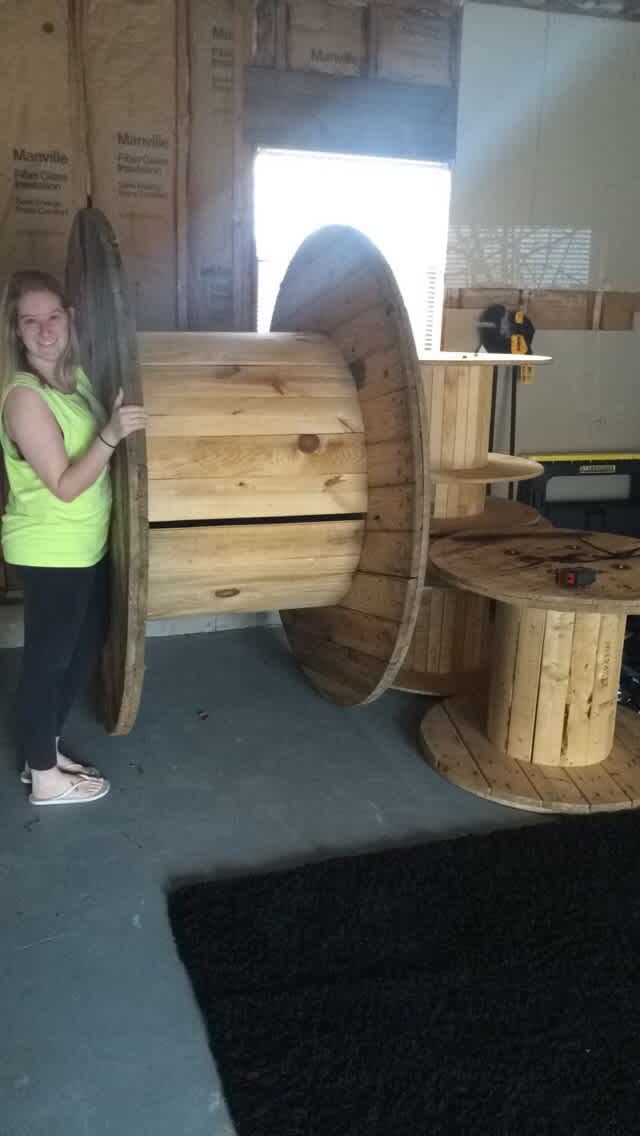 a woman standing next to a large wooden object in a room filled with wood pallets