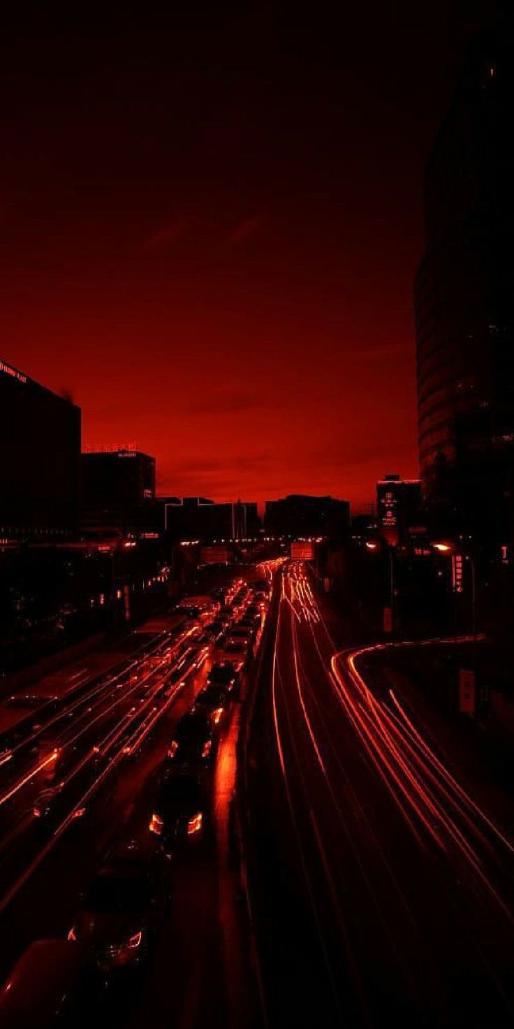 the city is lit up at night with long exposure and red light in the background