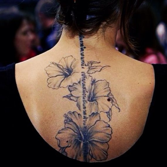 the back of a woman's neck with flowers tattooed on her upper and lower back