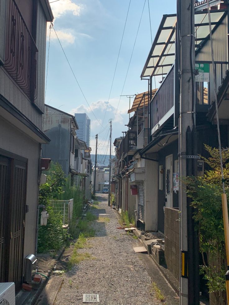 an alley way with buildings on both sides and power lines above the street in the distance