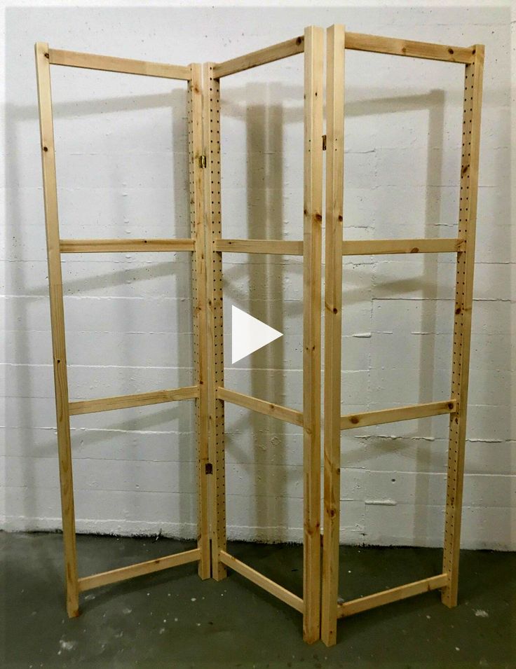 a wooden room divider in front of a white brick wall with an arrow pointing to it