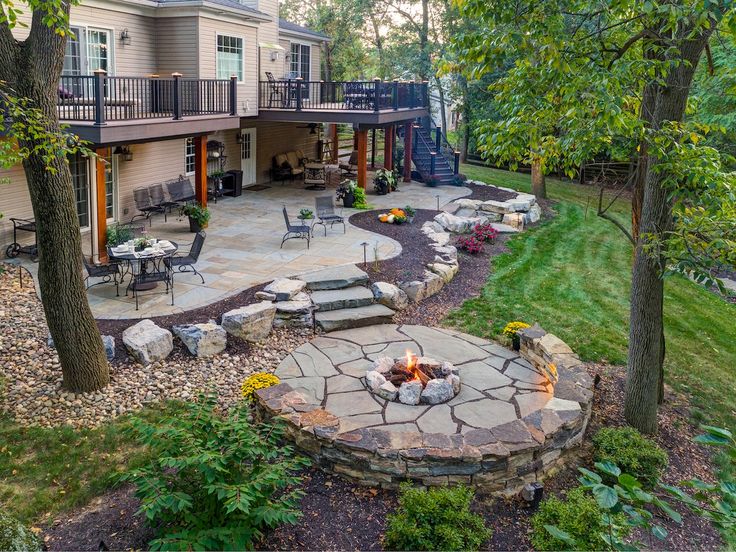 an outdoor patio and fire pit in the middle of a yard with landscaping around it