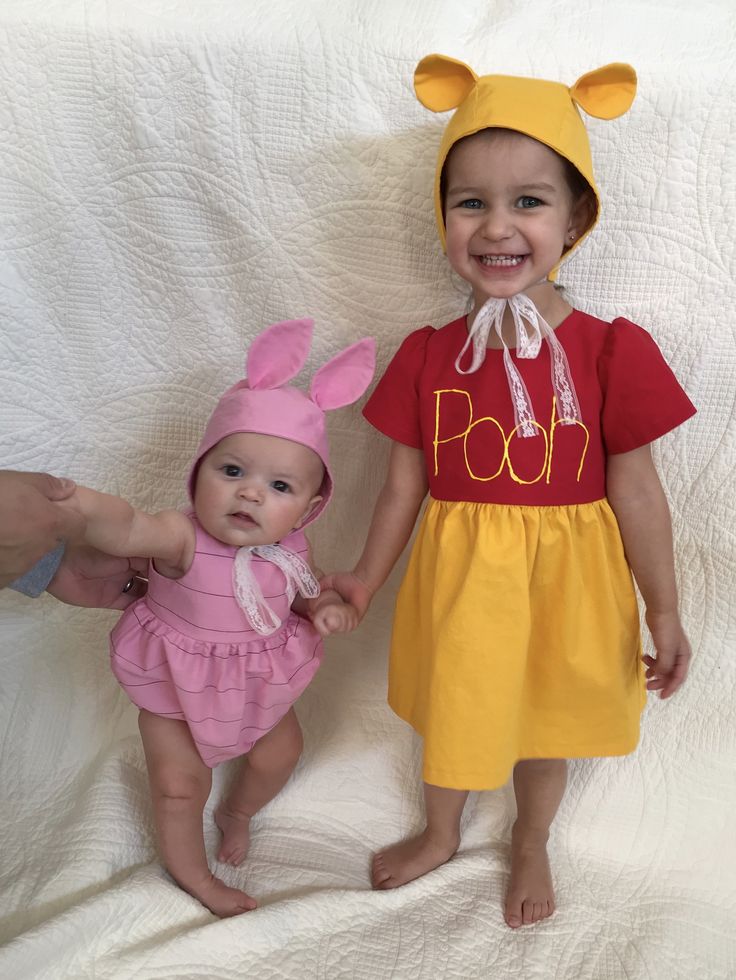 two young children dressed in costumes standing next to each other on a white sheeted surface