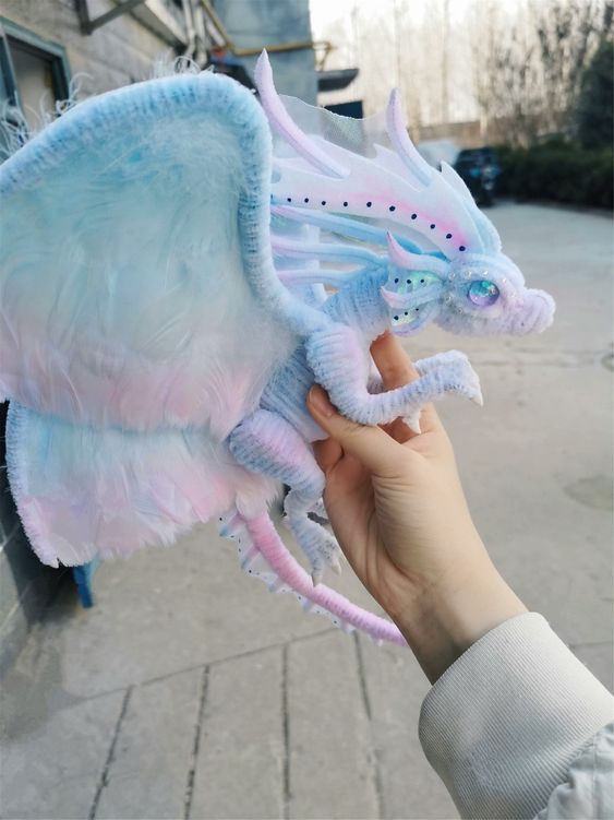 a person holding a stuffed dragon toy in their hand on the sidewalk next to a building