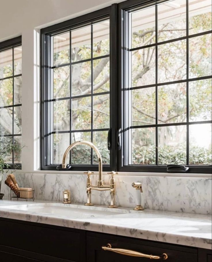 a kitchen with marble counter tops and gold faucets on the windowsills