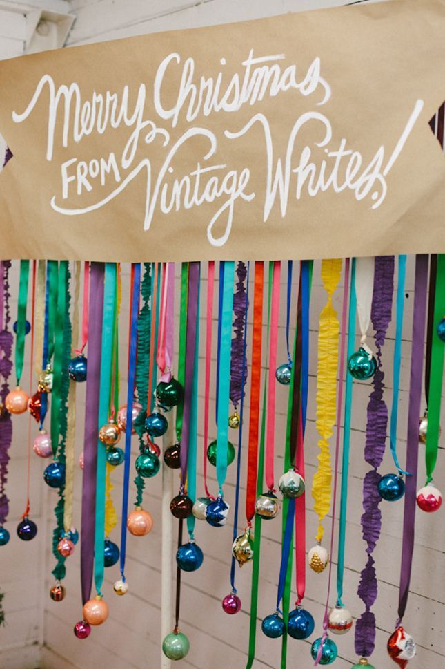 a merry christmas from vintage white's sign hanging on a wall with ribbons and ornaments