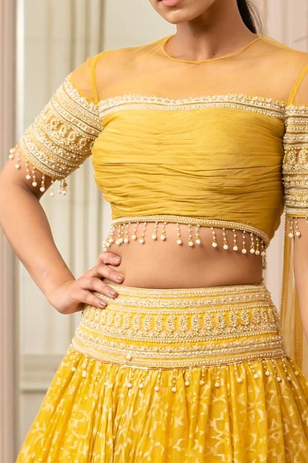 Mustard kalidar draped handloom lehenga with embroidered waistband and woven motifs. Paired with a fluted blouse with a sheer neckline and features attached tulle wings with fringing.
Component: 2
Pattern: Embroidered
Type Of Work: Paisley
Neckline: Round
Sleeve Type: Elbow Sleeves
Fabric: Lehenga : Handloom fabric , Blouse : Fluted Chiffon and Tulle
Color: Yellow
Other Details: 
Tulle wings
Sheer panels
Embroidered waistband
Closure:
Lehenga: Side zip
Occasion: Destination Wedding - Aza Fashion Handloom Lehenga, Yellow Drapes, Haldi Ceremony Outfit, Haldi Outfits, Lehenga Design, Lehenga Red, Wedding Saree Blouse, Yellow Lehenga, Wedding Saree Blouse Designs