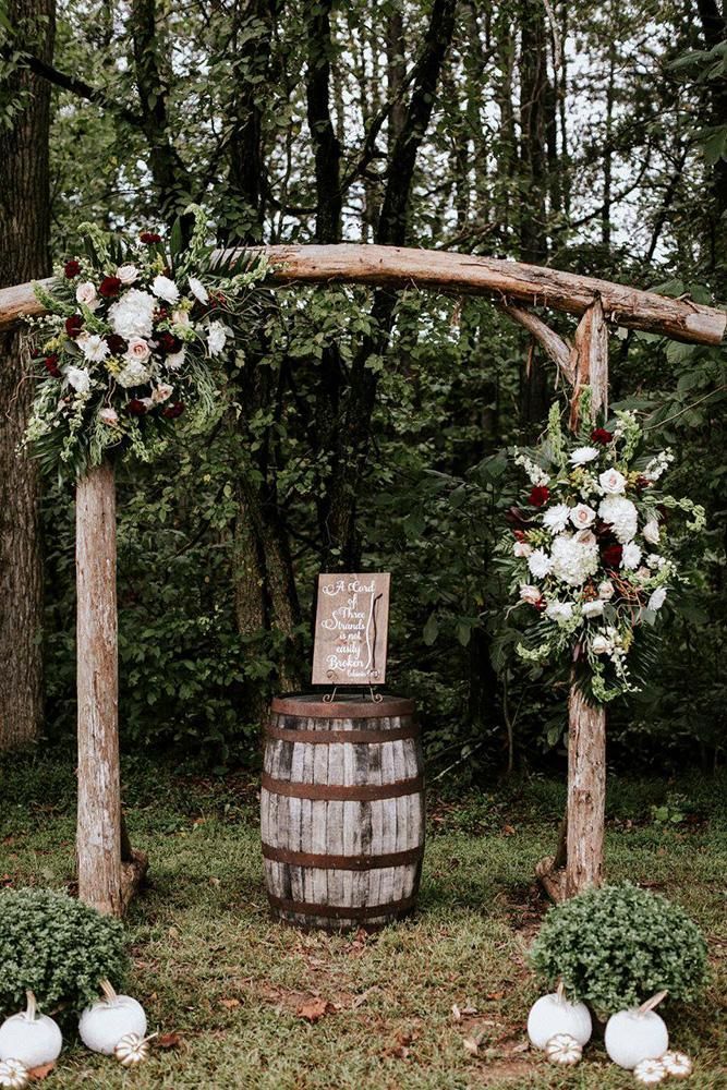 a wooden barrel with flowers and greenery on it is set up for an outdoor ceremony