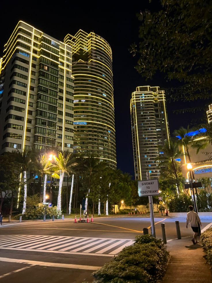 a city street at night with tall buildings in the background