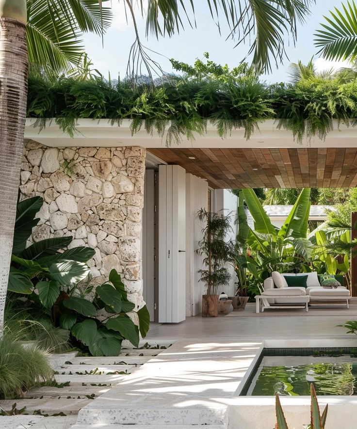 an outdoor living area with a pool surrounded by greenery