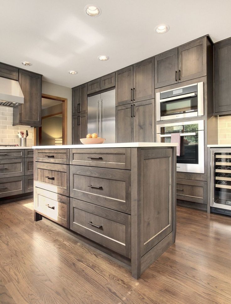 a large kitchen with wooden floors and gray cabinets