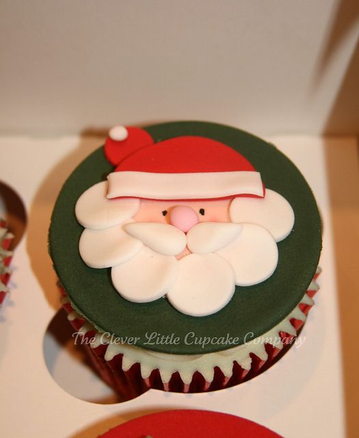 cupcakes decorated with frosting and santa claus's head on top are displayed