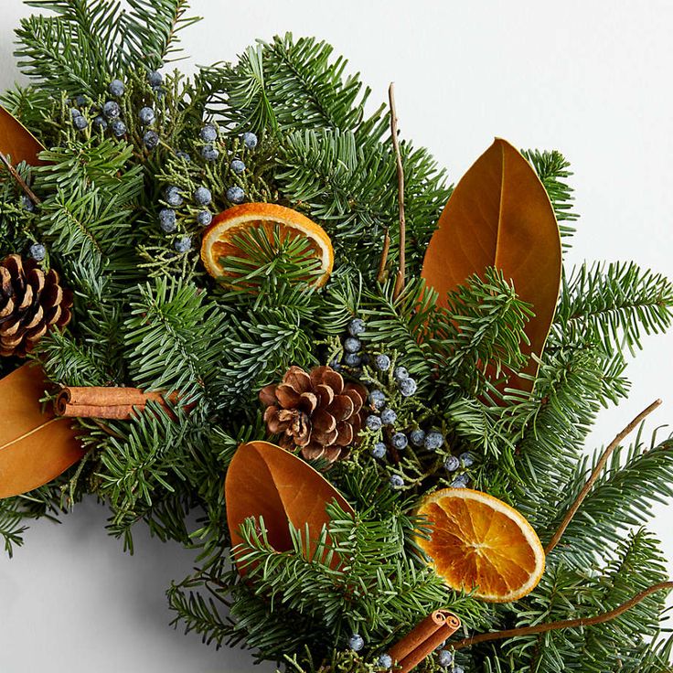 an arrangement of pine cones, orange slices and evergreen leaves