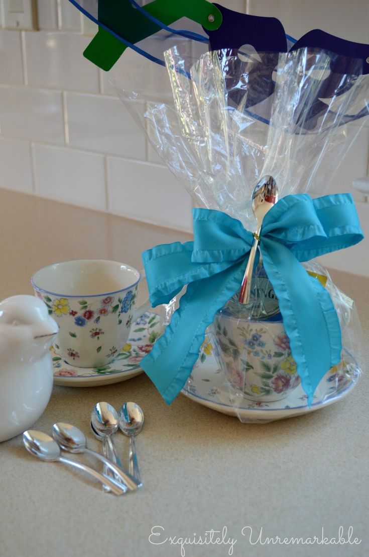 teacups and spoons are sitting on the counter with blue ribbons tied around them