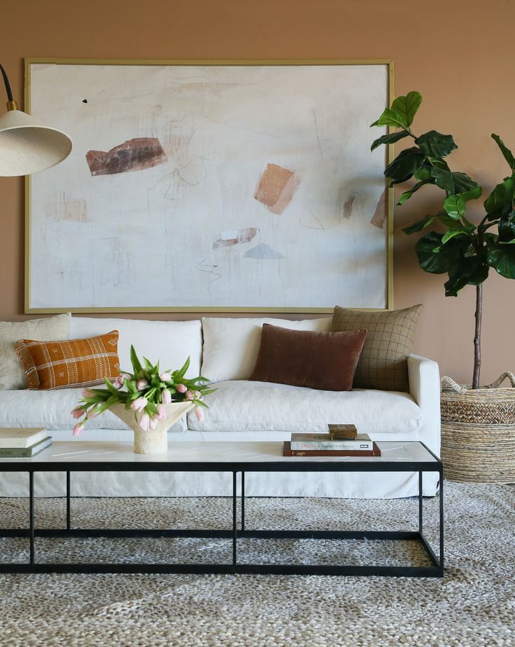 a living room with a couch, coffee table and potted plant in the corner