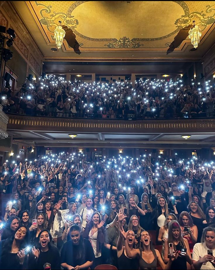 a group of people holding up their cell phones in the air with lights on them