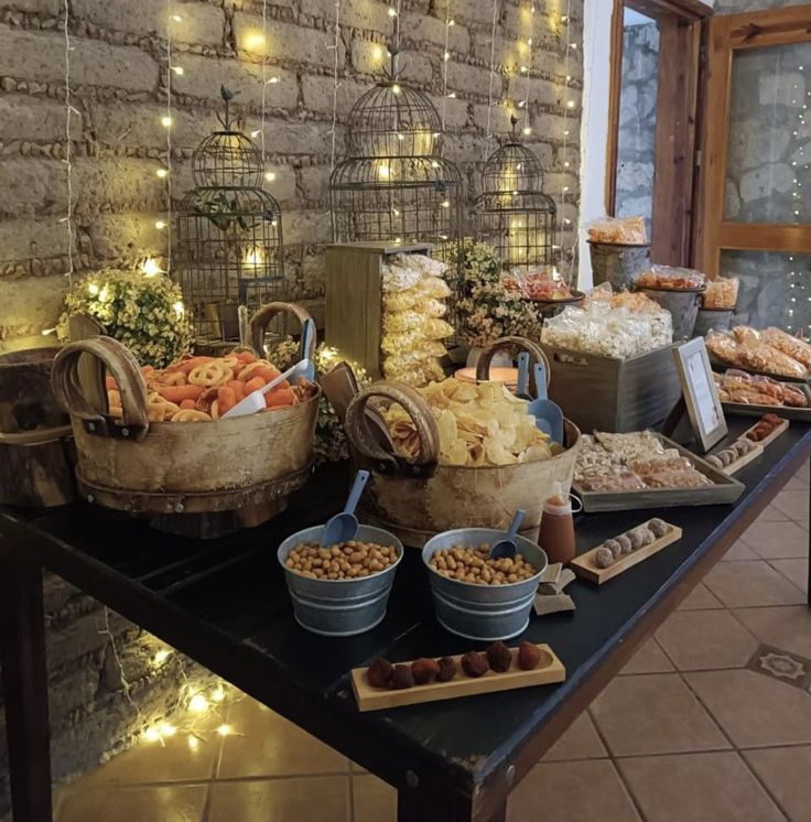 an assortment of food is displayed on a table in front of a brick wall with lights