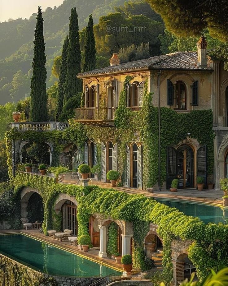 a large house with lots of greenery on the side of it and a pool in front of it