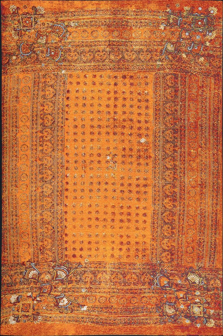 an orange and yellow rug with intricate designs on the border, in front of a black background