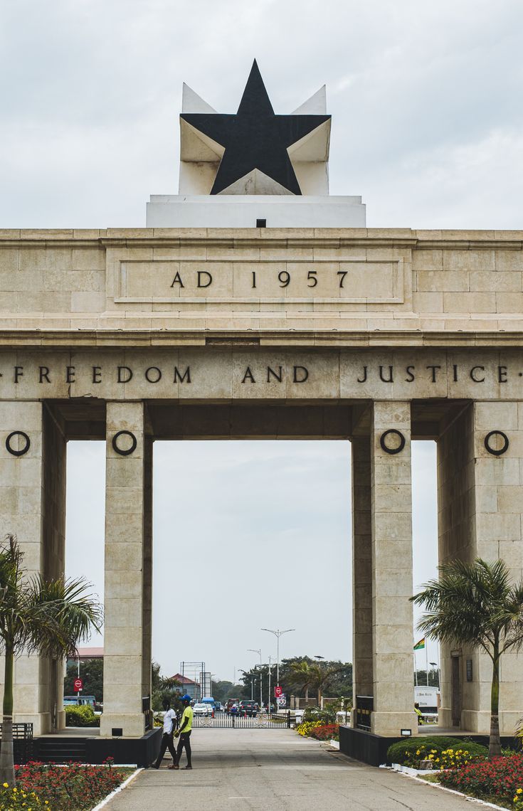 two people walking in front of the entrance to an army memorial with a star on top