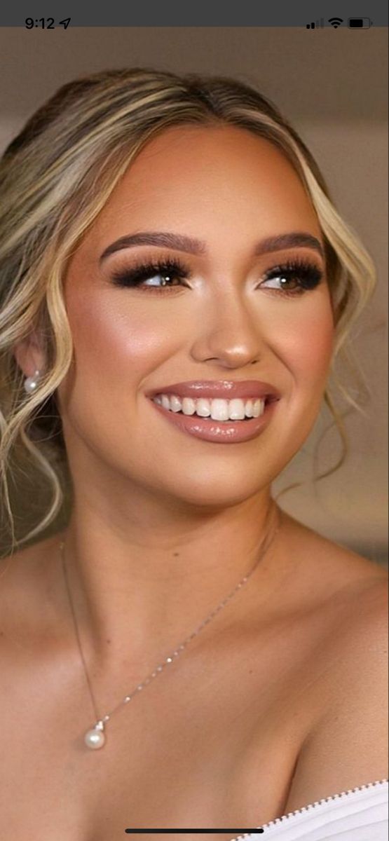 a woman with blonde hair wearing a white dress and smiling at the camera, she has her eyes closed