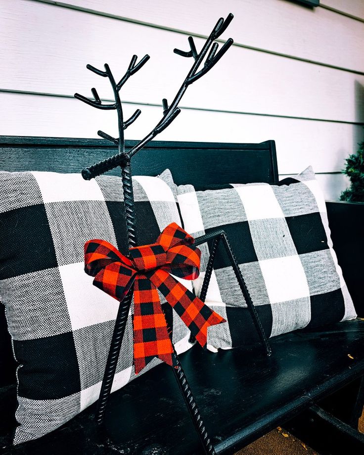 two black and white checkered pillows on a bench with a red bow tied to it