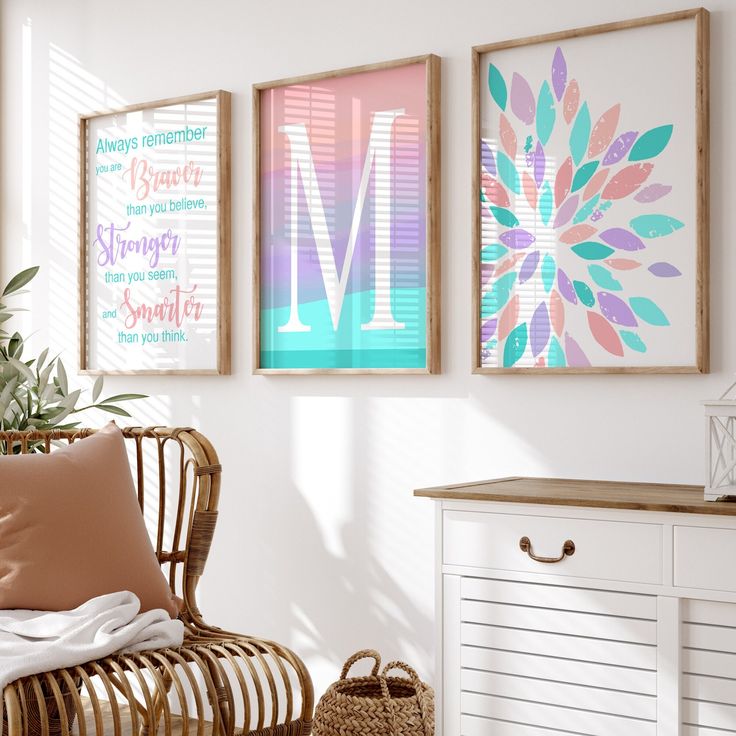 three framed pictures hang on the wall above a wicker chair in a white room