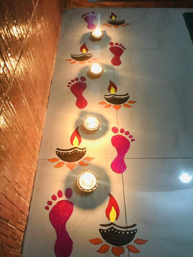 candles are lit in the shape of feet and footprints on a white tile floor with colorful designs