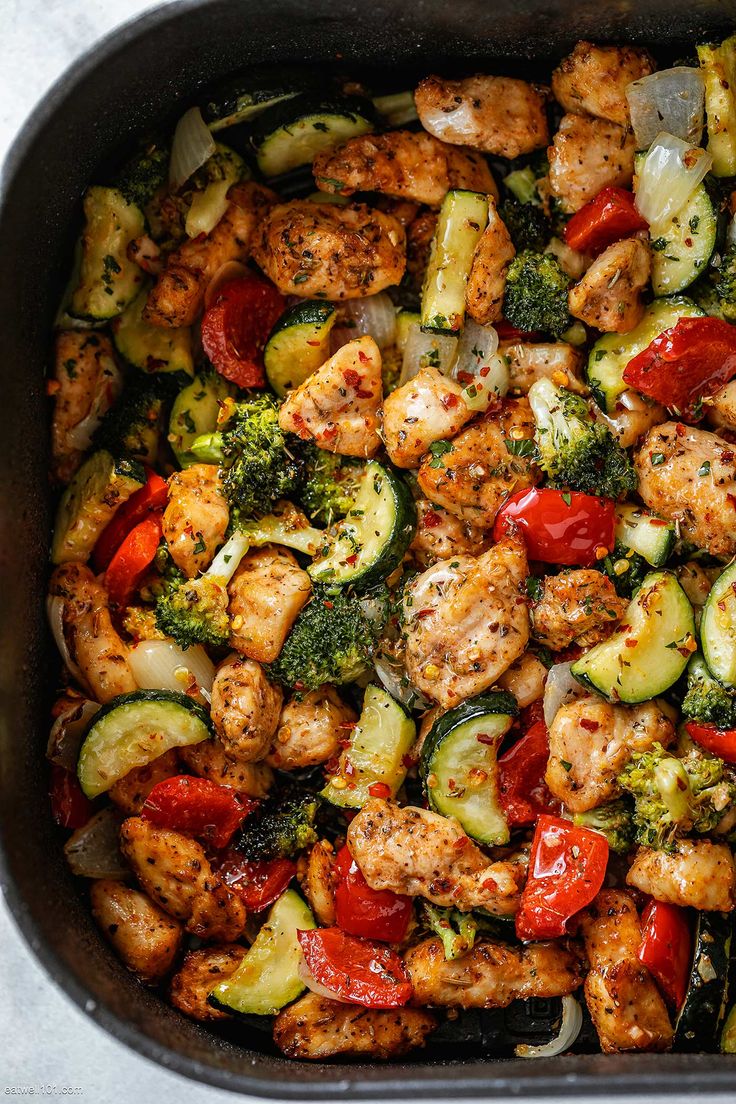 a pan filled with chicken and veggies on top of a table