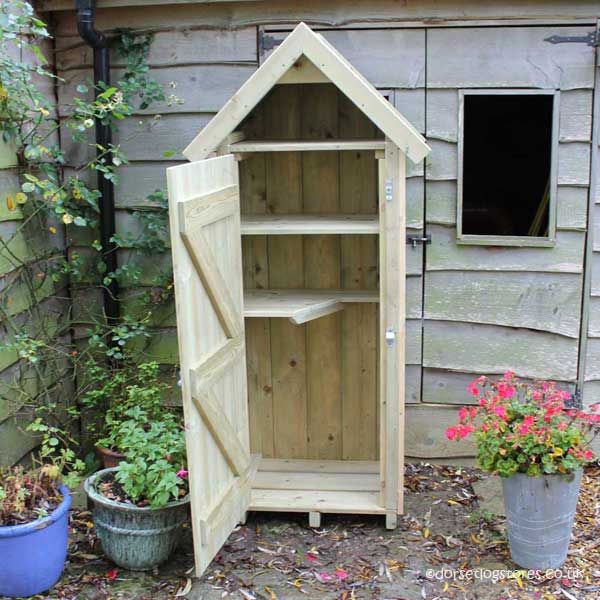 a wooden cabinet sitting next to a potted plant in front of a shed with flowers