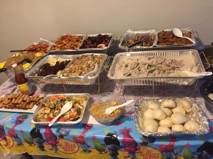 an assortment of food is displayed on a table with plastic containers and trays filled with different foods