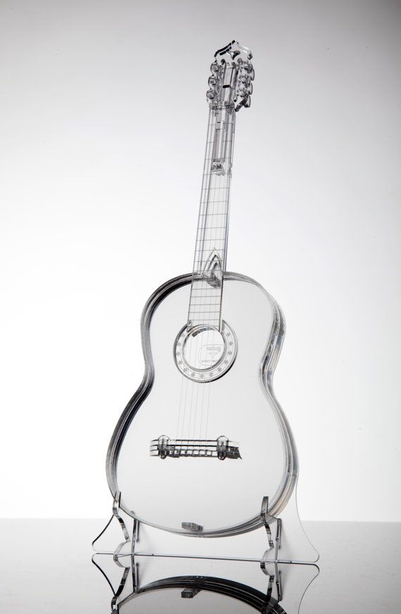 an acoustic guitar is displayed on a glass stand