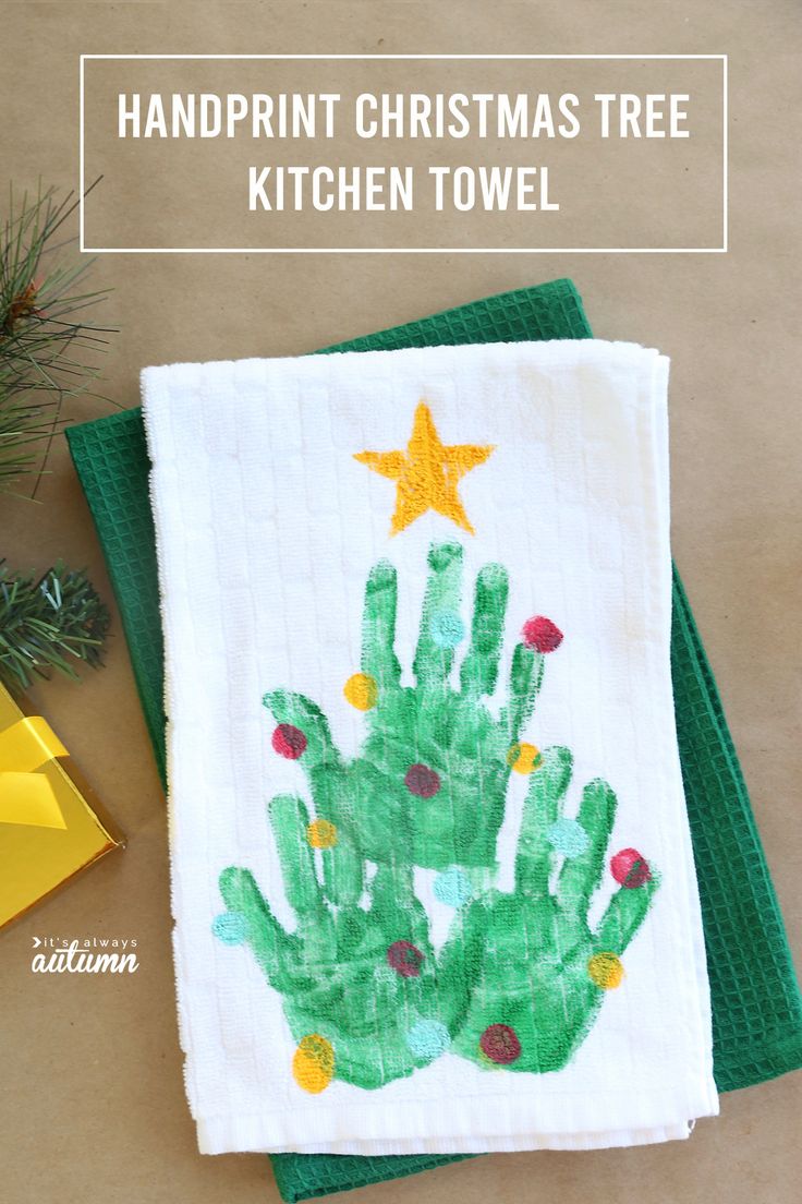 handprint christmas tree kitchen towel on top of green napkins next to pine cones