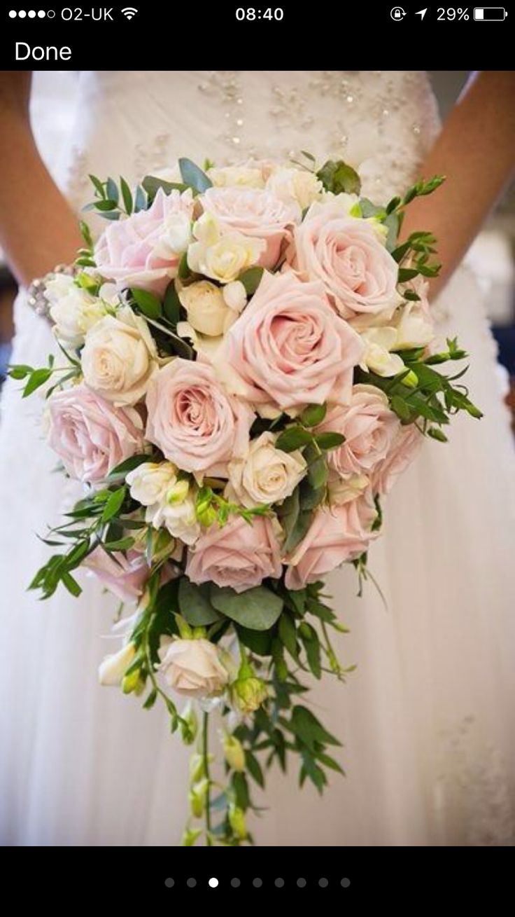 a bridal holding a bouquet of pink roses and greenery in her left hand