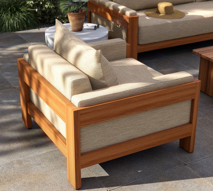 two couches and a coffee table on a patio with potted plants in the background