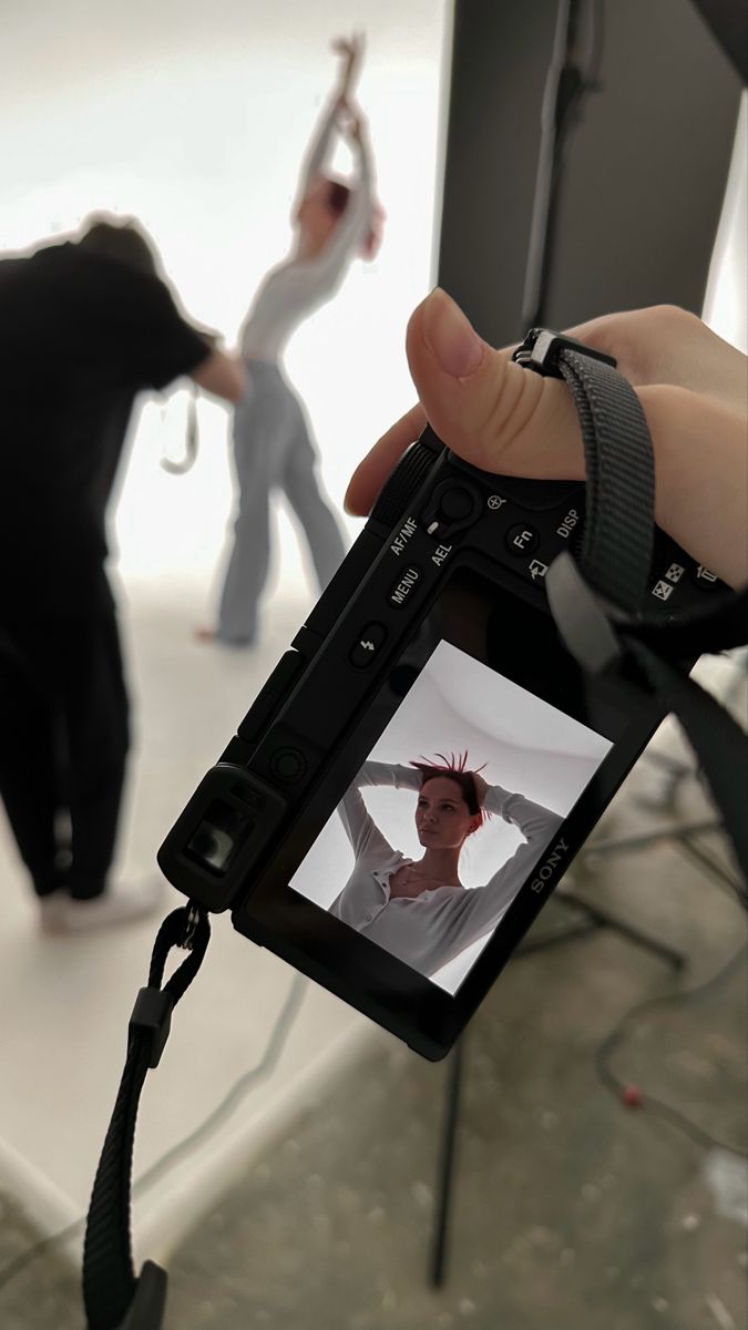 a person holding up a camera to take a photo with another person in the background