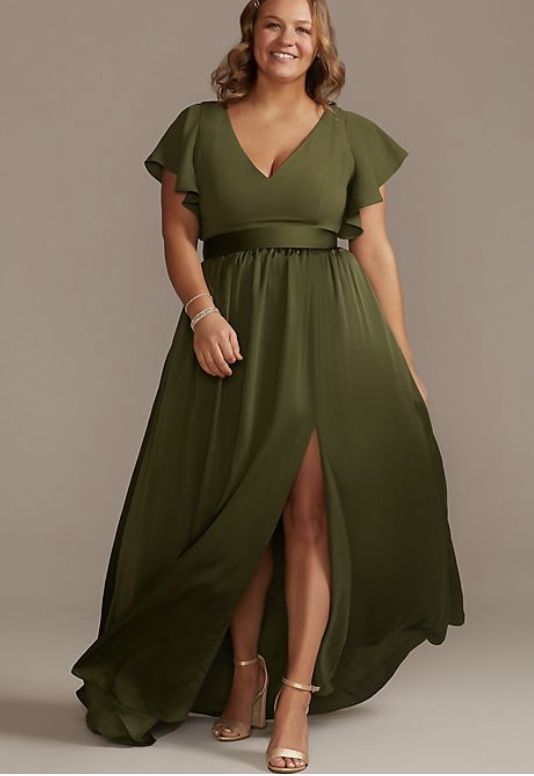 a woman wearing a green dress with a slited skirt and short sleeves, smiling at the camera